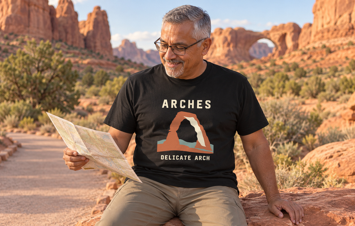 Illustrative lifestyle mockup of the Delicate Arch Graphic T-Shirt | Arches National Park on a black shirt in a generated outdoor scene.
