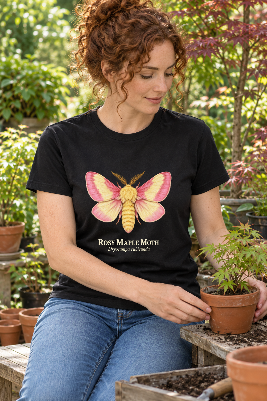 Illustrative lifestyle mockup of Rosy Maple Moth Natural History T-Shirt on a black shirt in a generated outdoor scene.