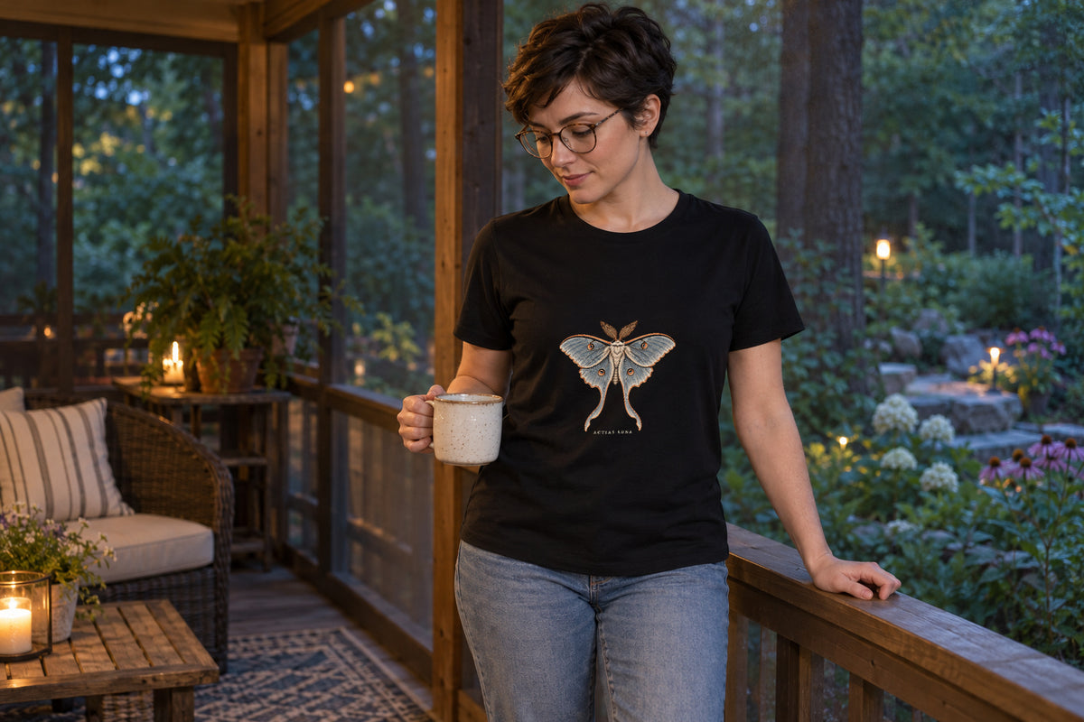 Illustrative lifestyle mockup of the Luna Moth Natural History T-Shirt on a black shirt in a generated scene.