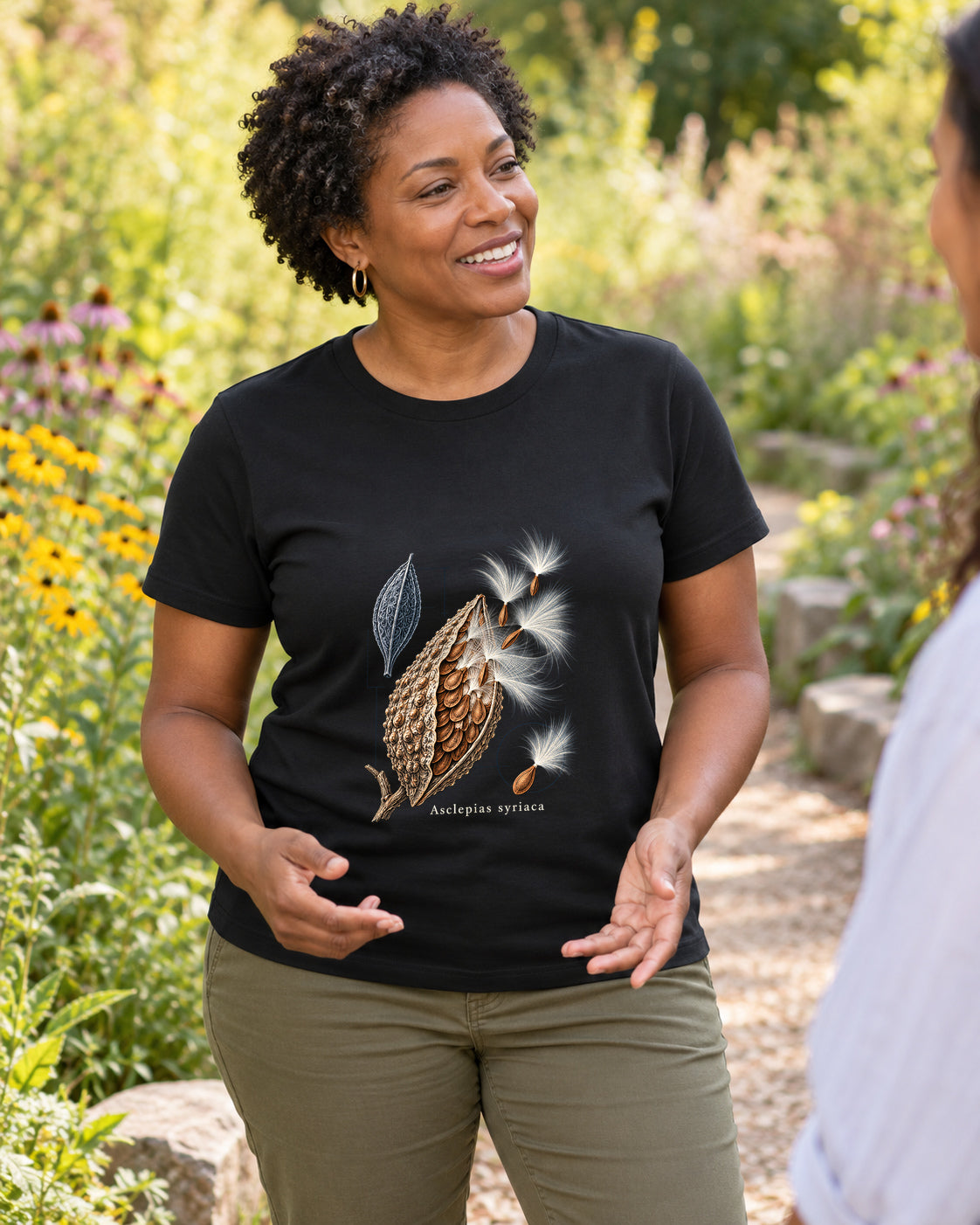 Illustrative lifestyle mockup of the Common Milkweed Seedpod Botanical T-Shirt on a black shirt in a generated scene.