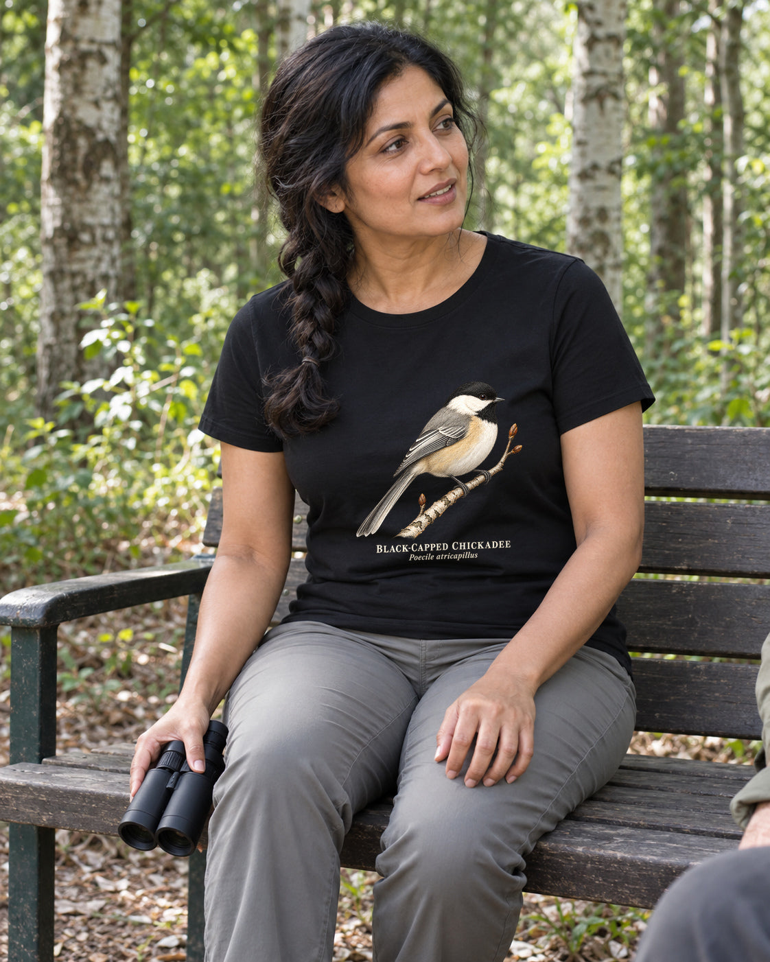 Illustrative lifestyle mockup of the Black-capped Chickadee Birdwatching T-Shirt on a black shirt in a generated scene.